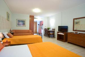 a hotel room with two beds and a television at Hotel Grand Nefeli in Vasiliki