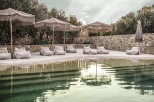 uma piscina de água com almofadas e guarda-sóis ao lado em Doryssa Boutique Hotel em Pythagoreio