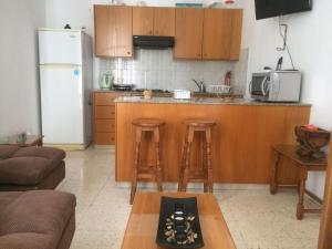 a kitchen with wooden cabinets and stools in a kitchen at Jacks Apartment in Paphos City