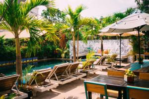 a patio with chairs and a pool with palm trees at Baby Elephant Boutique Hotel in Siem Reap