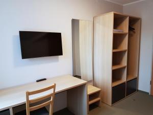 Habitación con escritorio y TV en la pared. en Hotel Jurate, en Nida