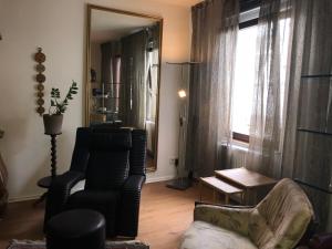 ein Wohnzimmer mit einem Stuhl, einem Sofa und einem Spiegel in der Unterkunft Gästewohnung im Logenhaus in Mainz