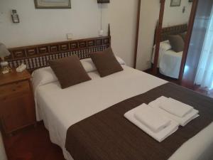 a bed with a white comforter and pillows at Hostal Esmeralda in Madrid