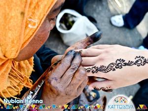 a man getting a henna tattoo on a persons hand at Kato Dool Wellness Resort in Aswan