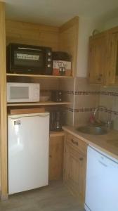 La cuisine est équipée d'un réfrigérateur blanc et d'un four micro-ondes. dans l'établissement Appartement Pyrénées 2000, à Font-Romeu