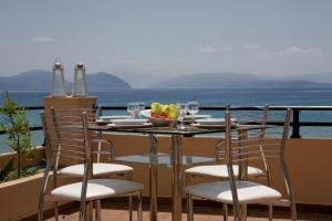 a table with chairs and a plate of food on a balcony at Hotel Grand Nefeli in Vasiliki