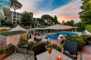 eine Außenterrasse mit einem Pool, Tischen und Sonnenschirmen in der Unterkunft Cardinal Hotel St. Peter in Rom