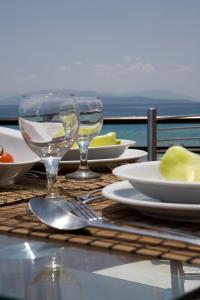 a table with plates and wine glasses on a table with the ocean at Hotel Grand Nefeli in Vasiliki