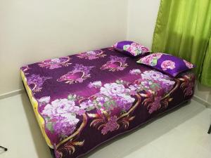 uma cama com um edredão roxo e almofadas em Chalet Desa Halban em Kangar