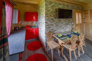 uma cozinha com armários vermelhos, uma mesa e cadeiras em Domek Regionalny Dan Pio em Zakopane