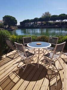 een tafel en vier stoelen op een terras met een rivier bij Marina village in Saint Cyprien Plage