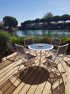 einen Tisch und vier Stühle auf einer Terrasse mit einem Fluss in der Unterkunft Marina village in Saint Cyprien Plage