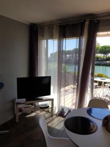 uma sala de estar com televisão e uma grande janela em Marina village em Saint-Cyprien-Plage