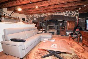 a living room with a couch and a stone fireplace at Le Cottage Lavastrie in Lavastrie
