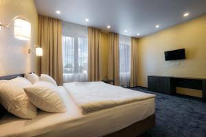 um quarto com uma grande cama branca e uma televisão em Komatek Hotel em Ecaterimburgo