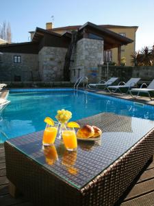 a table with two glasses of orange juice and a plate of bread at Alltominho – Villas Summer Holidays in Afife
