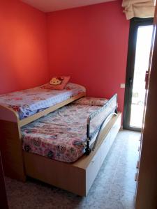 リャゴステラにあるMENESES, BONITA CASA EN LLAGOSTERA CON PISCINA Y WIFI GRATUITOの赤い壁のドミトリールームの二段ベッド2台