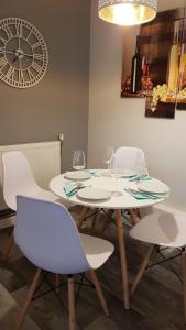 a table with four chairs and a clock on the wall at New Contemporary Flat minutes from Airport & NEC in Marston Green