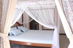 un letto a baldacchino con tende bianche di Villa Sureka a Hikkaduwa