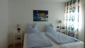 een slaapkamer met een bed met witte lakens en kussens bij Ferienwohnung Ute in Kandern
