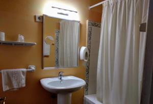 y baño con lavabo, espejo y ducha. en Hotel Pedro Torres, en Cuenca