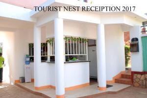 a white building with columns and a sign that reads tourist nest reception at Tourist Nest Hotel in Kampala