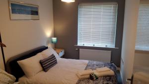 um quarto com uma cama com almofadas e uma janela em New Contemporary Flat minutes from Airport & NEC em Marston Green