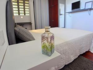 a glass bottle sitting on a white table next to a bed at Società Agricola La Staccionata in Staranzano