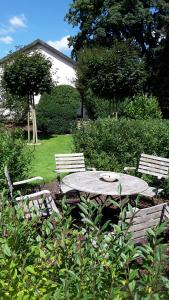 een tafel en twee stoelen in een tuin met een tafel en banken bij Landhaus Zur Eiche in Sittensen