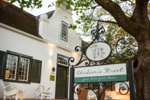 um sinal em frente a um edifício com uma árvore em Akademie Street Boutique Hotel em Franschhoek