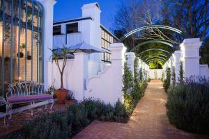 a walkway leading to a white building with an umbrella at Akademie Street Boutique Hotel in Franschhoek