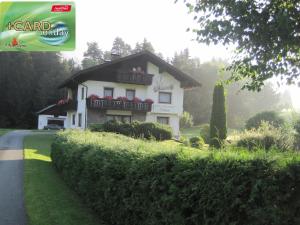 ein weißes Haus mit roten Blumen auf dem Balkon in der Unterkunft Ferienwohnungen Tillian in Hermagor