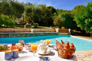 a table with food and drinks next to a swimming pool at Chambres d'hôtes Villa Cardabella in Le Tignet