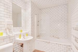 a white bathroom with a sink and a tub at Grand Place Charbon Residence in Brussels