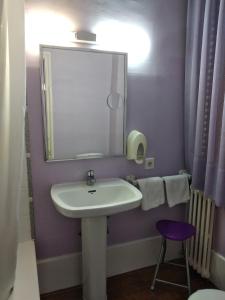 a bathroom with a sink and a mirror and a stool at Hotel Pedro Torres in Cuenca