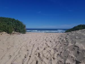 a sandy beach with footprints in the sand and the ocean at Pili Pili Beach Cabanas in Sedgefield