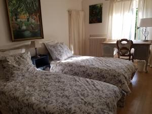 een slaapkamer met 2 bedden, een bureau en een raam bij Couleurs et jardin in Saint-Augustin