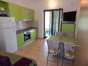 eine Küche mit grünen Schränken und einem Tisch mit Stühlen in der Unterkunft Apartmani Nin in Nin
