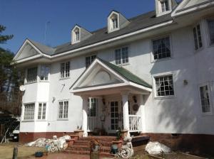 a large white house with a roof at Petit Hotel and Restaurant Air Mail in Hakuba