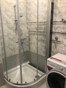 a shower with a glass door next to a washing machine at Apartment "Flowers" in Rīga