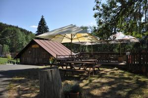 a group of picnic tables with umbrellas in front of a barn at Penzion Pohádka in Hojsova Stráž