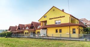 une maison jaune avec une clôture devant elle dans l'établissement Nemes Apartmanház, à Hévíz