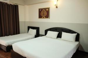 two beds in a hotel room with white sheets at Puangpech Hotel Lampang in Lampang