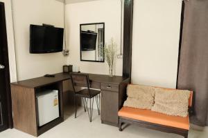 Zimmer mit einem Schreibtisch, einem TV und einem Stuhl in der Unterkunft Puangpech Hotel Lampang in Lampang