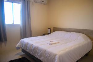 a bedroom with a white bed with a window at Hotel Marrocos in Pelotas