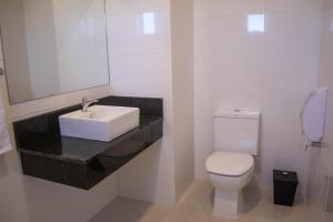 a white bathroom with a sink and a toilet at Hotel Marrocos in Pelotas