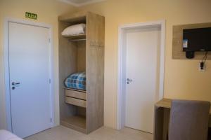 a room with a closet with a bed and a door at Hotel Marrocos in Pelotas