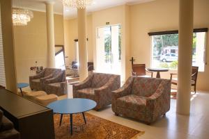 a lobby with chairs and tables and a chandelier at Hotel Marrocos in Pelotas