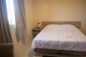 a bedroom with a white bed with a window at Hotel Marrocos in Pelotas