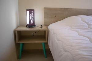 a bedside table with a book on it next to a bed at Hotel Marrocos in Pelotas